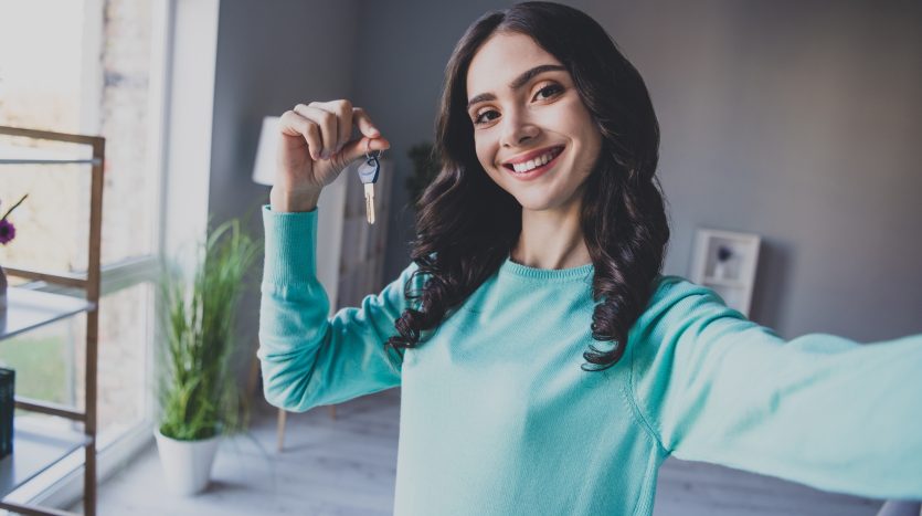 Ragazza giovane con in mano chiavi di una casa appena comprata