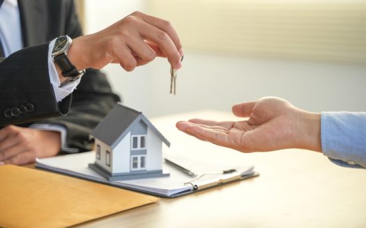 Mano di un uomo con chiavi in mano che le allunga a un altro uomo davanti a una scrivania