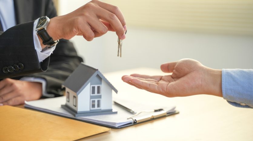 Mano di un uomo con chiavi in mano che le allunga a un altro uomo davanti a una scrivania