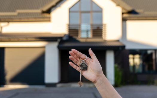 Mano di una ragazza con delle chiavi in mano davanti a una casa