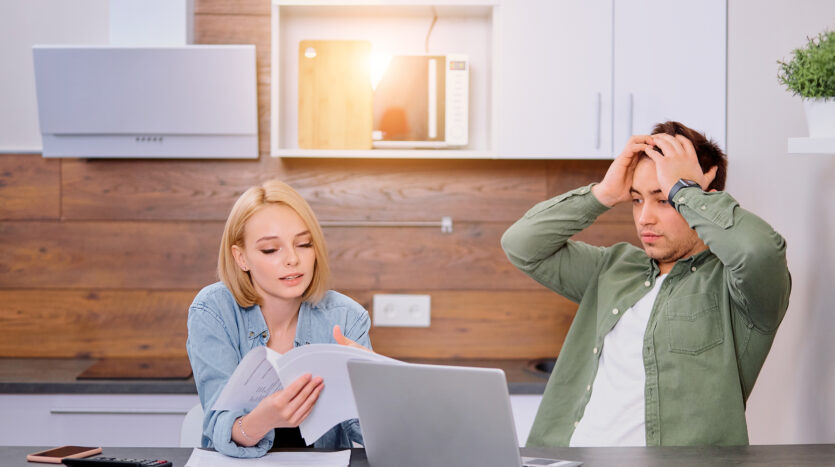 un uomo e una donna disperati davanti al computer, intenti a interpretare un documento complesso